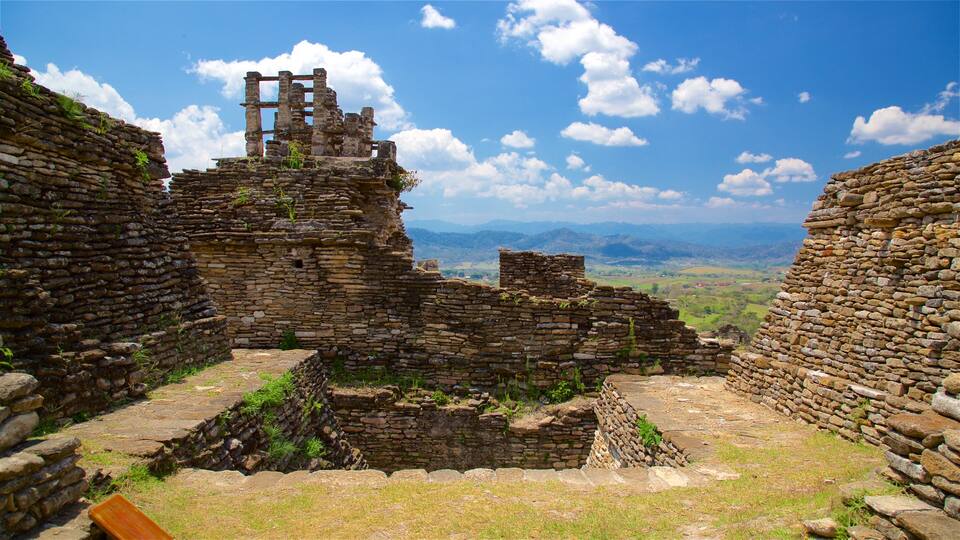 Ancient stone ruins with a mountainous landscape in the background.