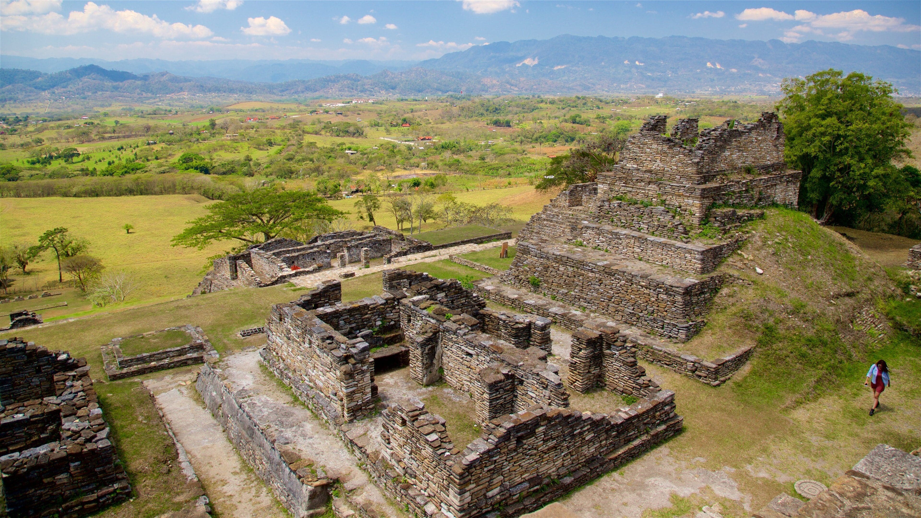 Ancient stone ruins with a view of a lush valley and distant mountains.