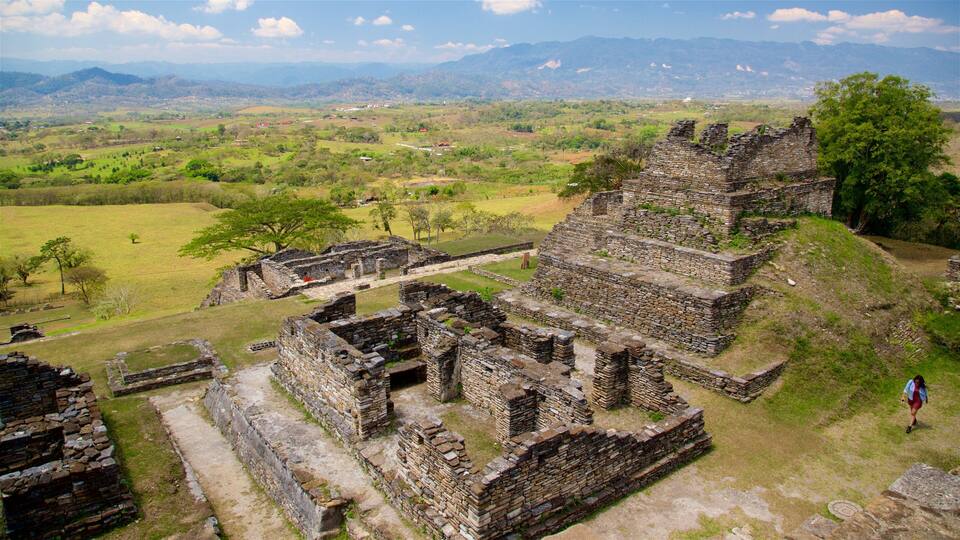 Ancient stone ruins with a view of a lush valley and distant mountains.