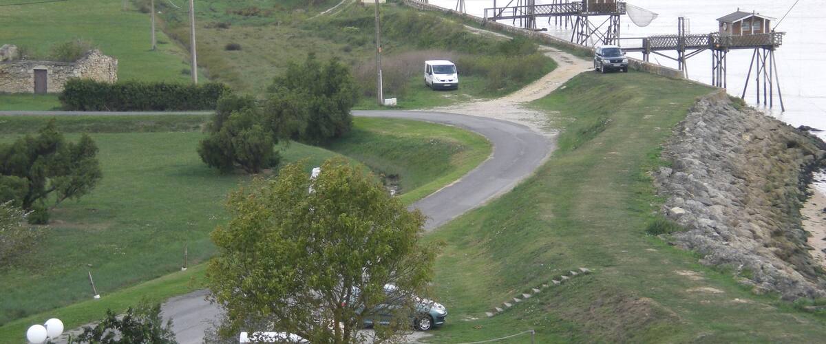 A coastal area with a road curving along the shore, a white van parked on the side, and a fishing pier extending into the water.