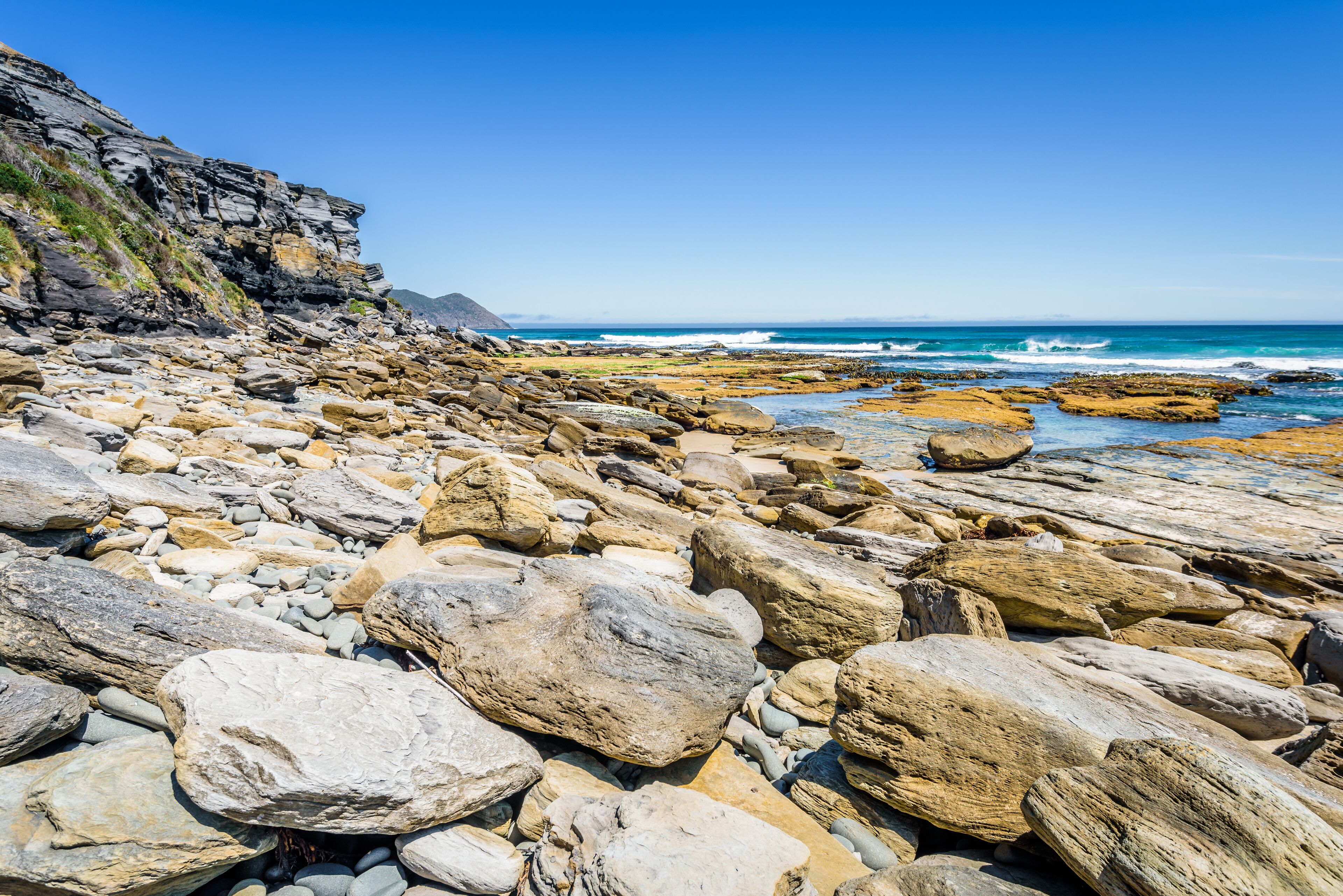 Amazing view to stunning rocky sandy beach deep blue water of southern ocean antarctica on warm sunny day with blue sky after hiking on to South Cape Bay, South-West National Park, Tasmania, Australia
