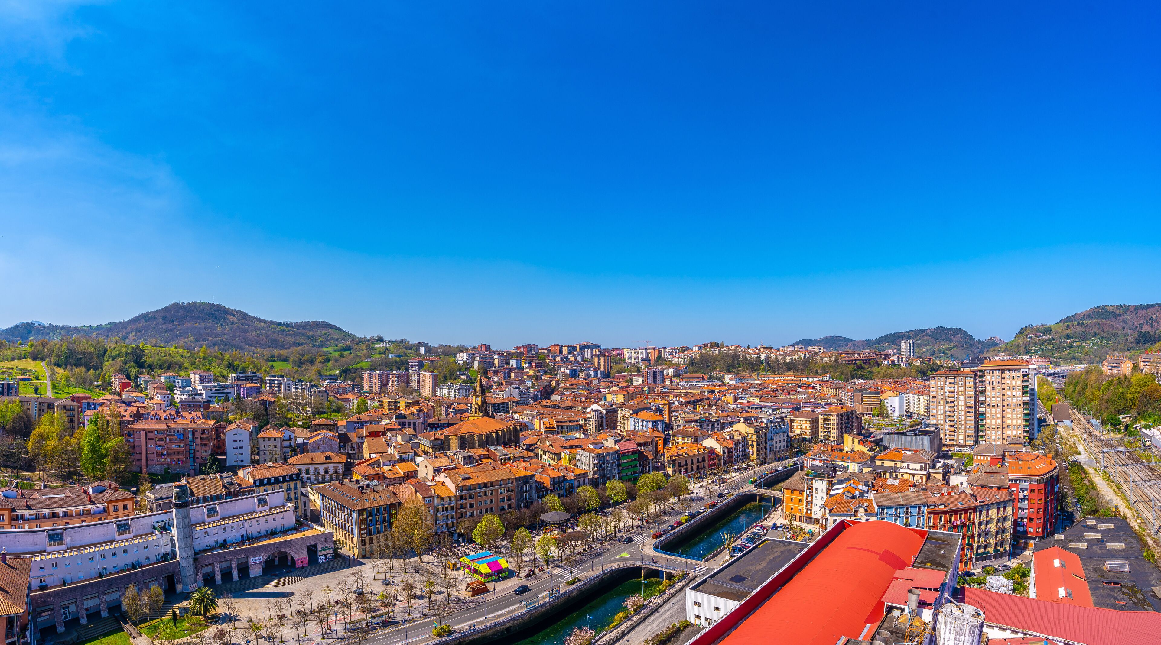 A cityscape with a river, historic buildings, and a mountainous backdrop.
