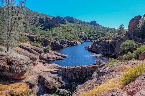 A river winding through a rocky canyon with green vegetation and a clear blue sky.
