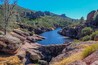 A river winding through a rocky canyon with green vegetation and a clear blue sky.