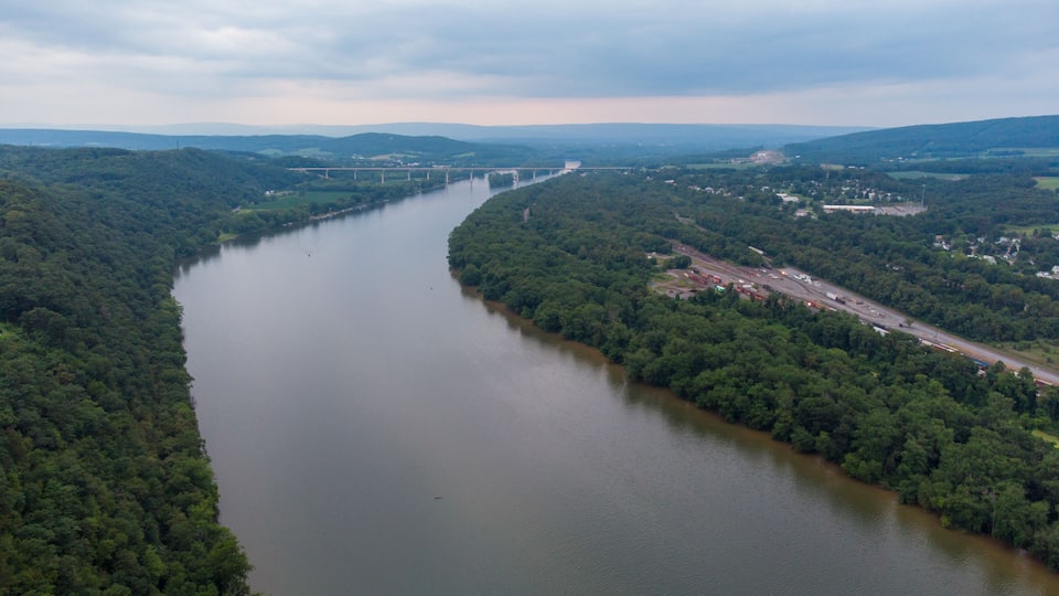 A river winding through a densely forested valley with a bridge in the distance.