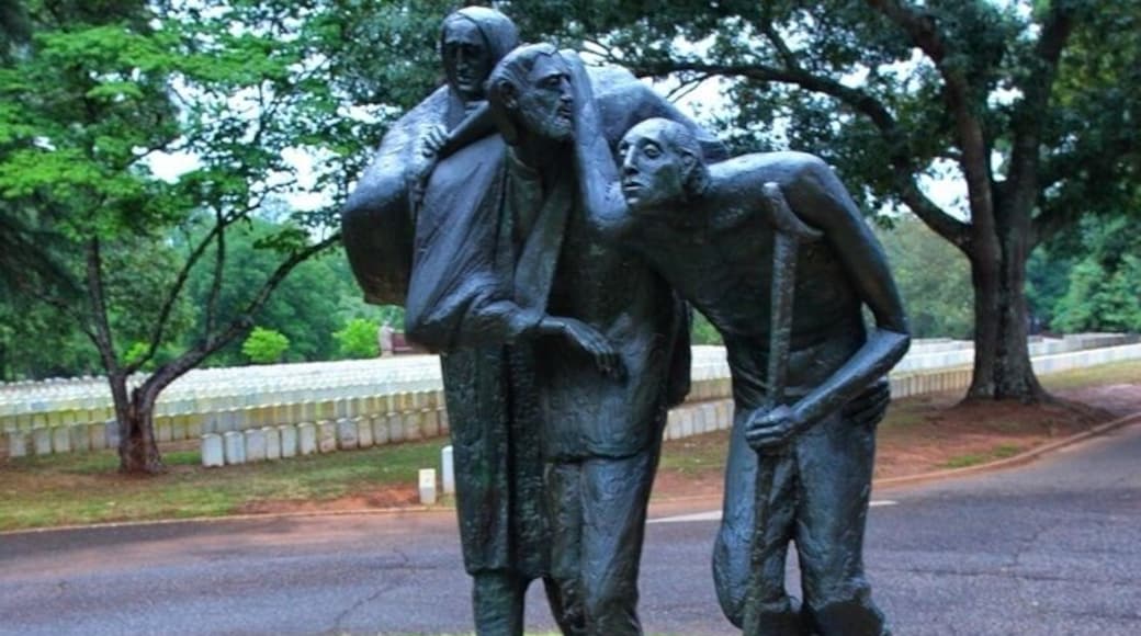 President Jimmy Carter, who had worked toward's Andersonville's inclusion in the National Park System, encouraged the State of Georgia to place a monument at the park.
Dedicated on Memorial Day 1976, the Georgia Monument serves as a memorial to all American prisoners of war.
In his own words, sculptor William Thompson described his imagery and intent in designing the Georgia Monument:
In creating a sculpture for Andersonville National Historic Site, it was my intention to design a monument which is sculpturally strong and humanly moving.
This sculpture is dedicated to all American prisoners involved in all American wars over our country's birth up to the present. The sculpture is designed to have a universal quality, and no reference to any particular uniform or specific details have been made. The accent has been placed on the inner struggle and strength of the prisoners.
The statue is intended to speak directly to the viewer in its formal sculpture statement, and about the strength of brotherhood and man's dependence upon God, in its symbolism.
The placement of the figures marching in a broken line is to call to mind the formations that all prison camps require. The placement of the prisoners on the incline plane of the granite base emphasizes the fact that it is an uphill struggle just to survive under prison camp conditions. These men have exhausted their human resources and now look beyond one another to God for strength. (Note description on the base.)
The two figures in front are united by the overlapping of their arms, which accent the supportive nature of the group. The support of a fellow prisoner often made the difference between life and death, and the sculpture composition and gesture of the monument is to bring this fact into dramatic focus. Men are often captured as a result of their battle wounds, and others develop maladies and injuries during their imprisonment, therefore, I decided to depict my prisoners with wounds.