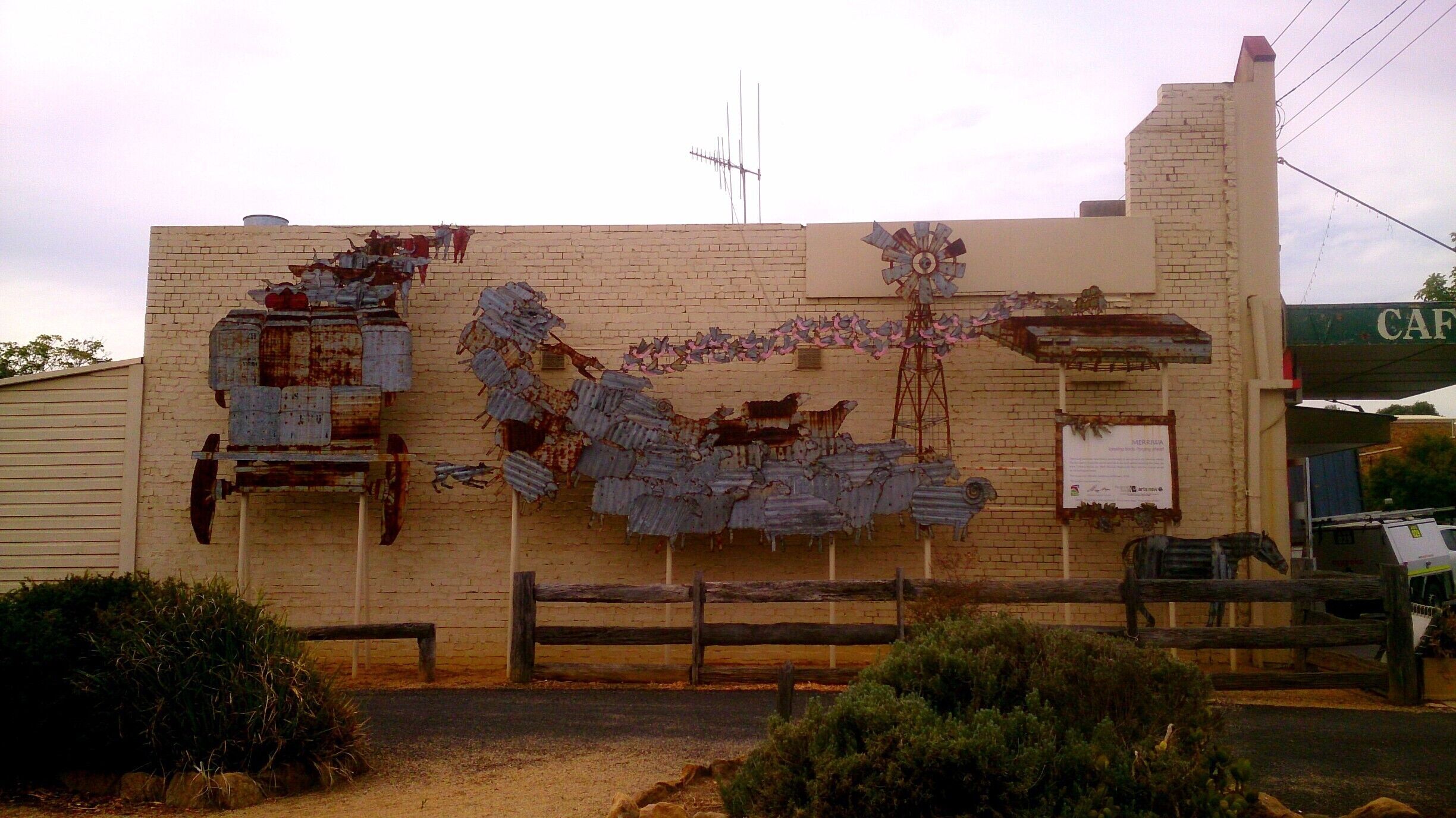 A building with a brick facade, a windmill, and a sign that reads "CAFE".