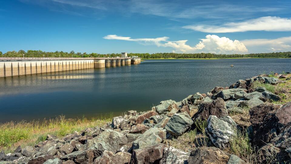 A calm lake with a dam and rocky shoreline.