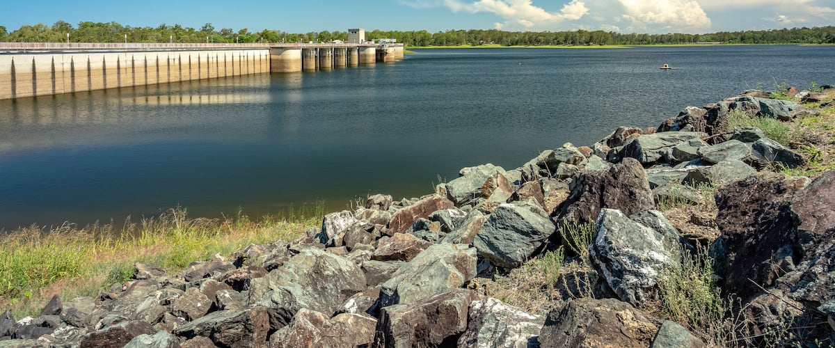A calm lake with a dam and rocky shoreline.