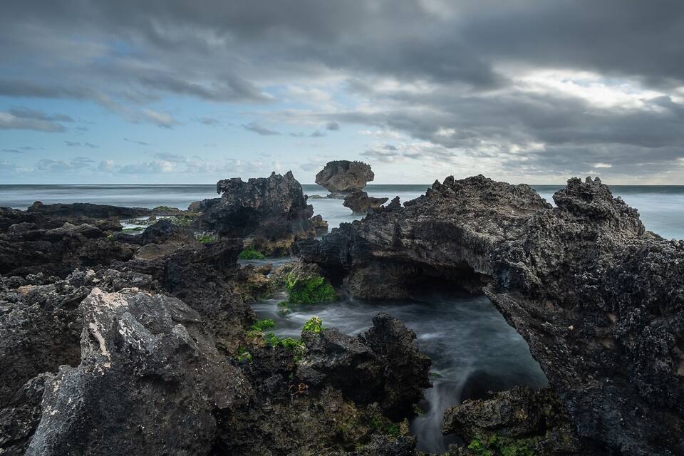 A rugged coastal landscape with prominent rocky formations and a narrow water channel.