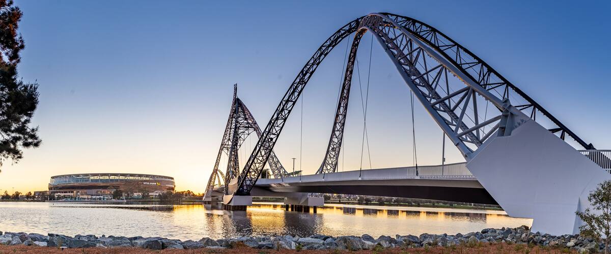 A roller coaster, a bridge, and a stadium by a body of water.