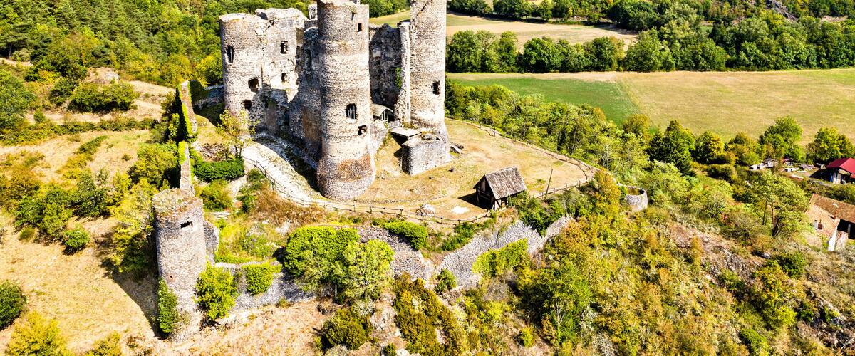 A medieval castle surrounded by lush green hills and fields.