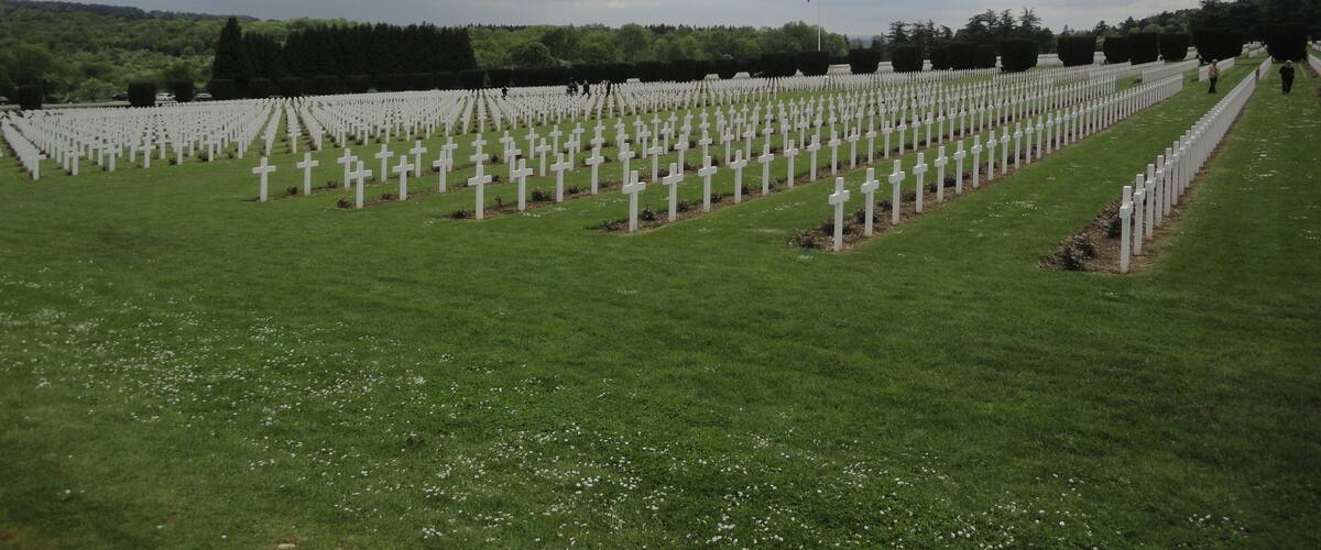 Ein Friedhof mit Reihen weißer Kreuze unter einem bewölkten Himmel.