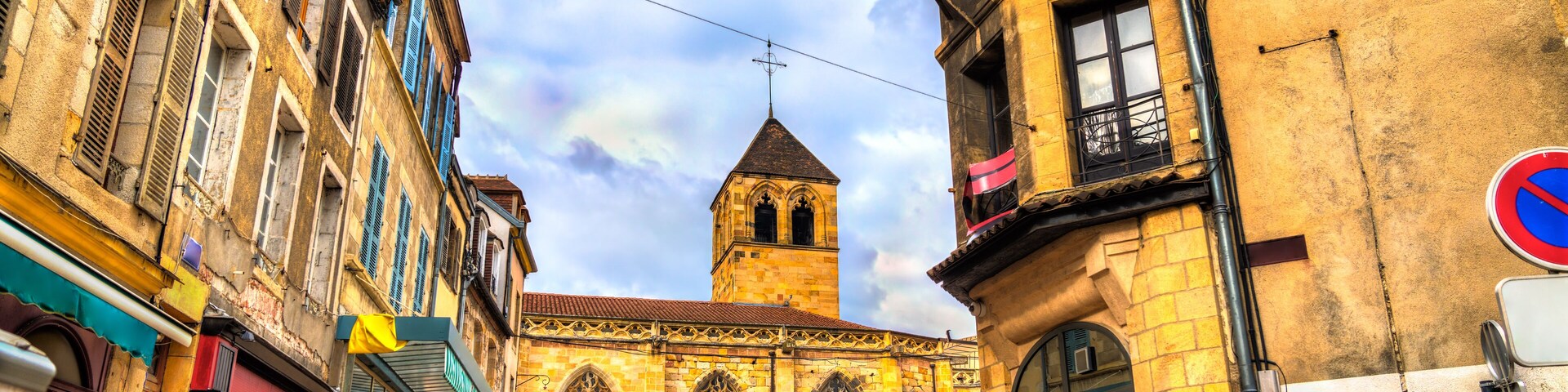 Uma rua histórica com torre de igreja, calçada de pedra e edifícios tradicionais.