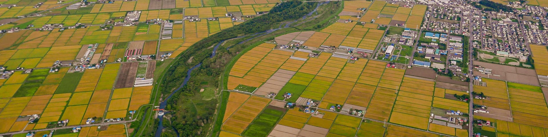 After taking off from Asahikawa Airport in Hokkaido, Japan, an aerial view reveals Higashikagura Town to the east (in the middle right) and the Chubetsu River (in the center).
