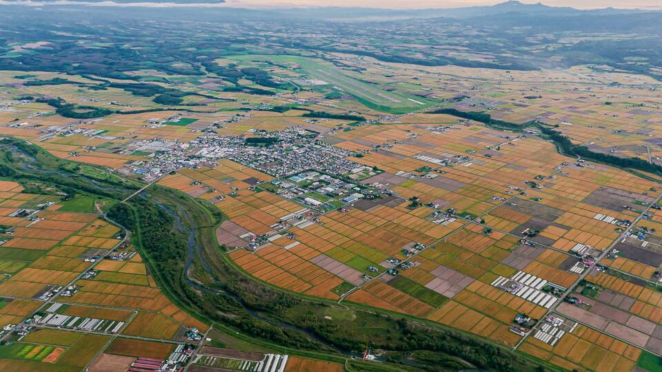 An aerial view of a rural landscape with fields, a winding river, and a small town.