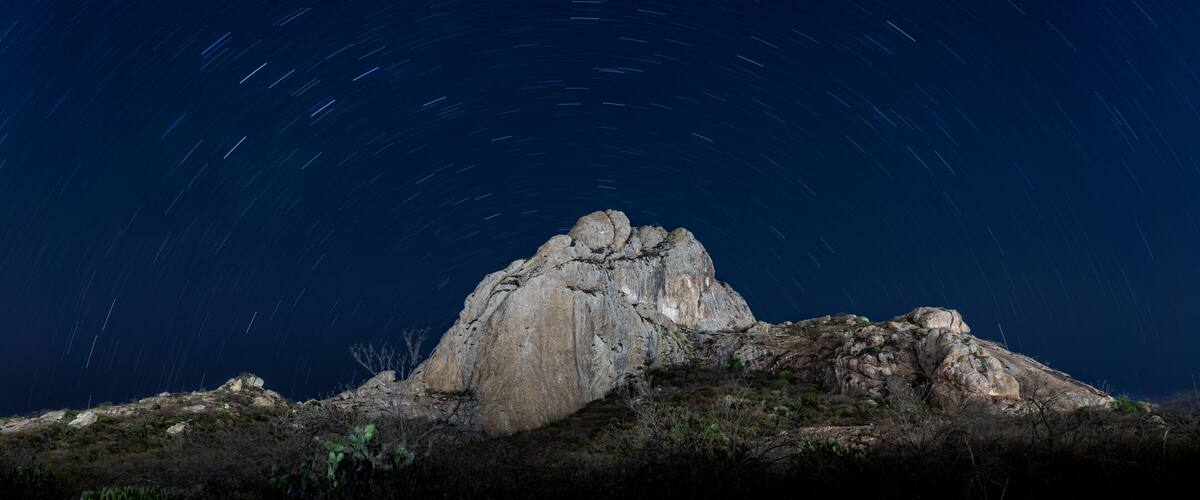 A rocky mountain peak under a starry night sky.
