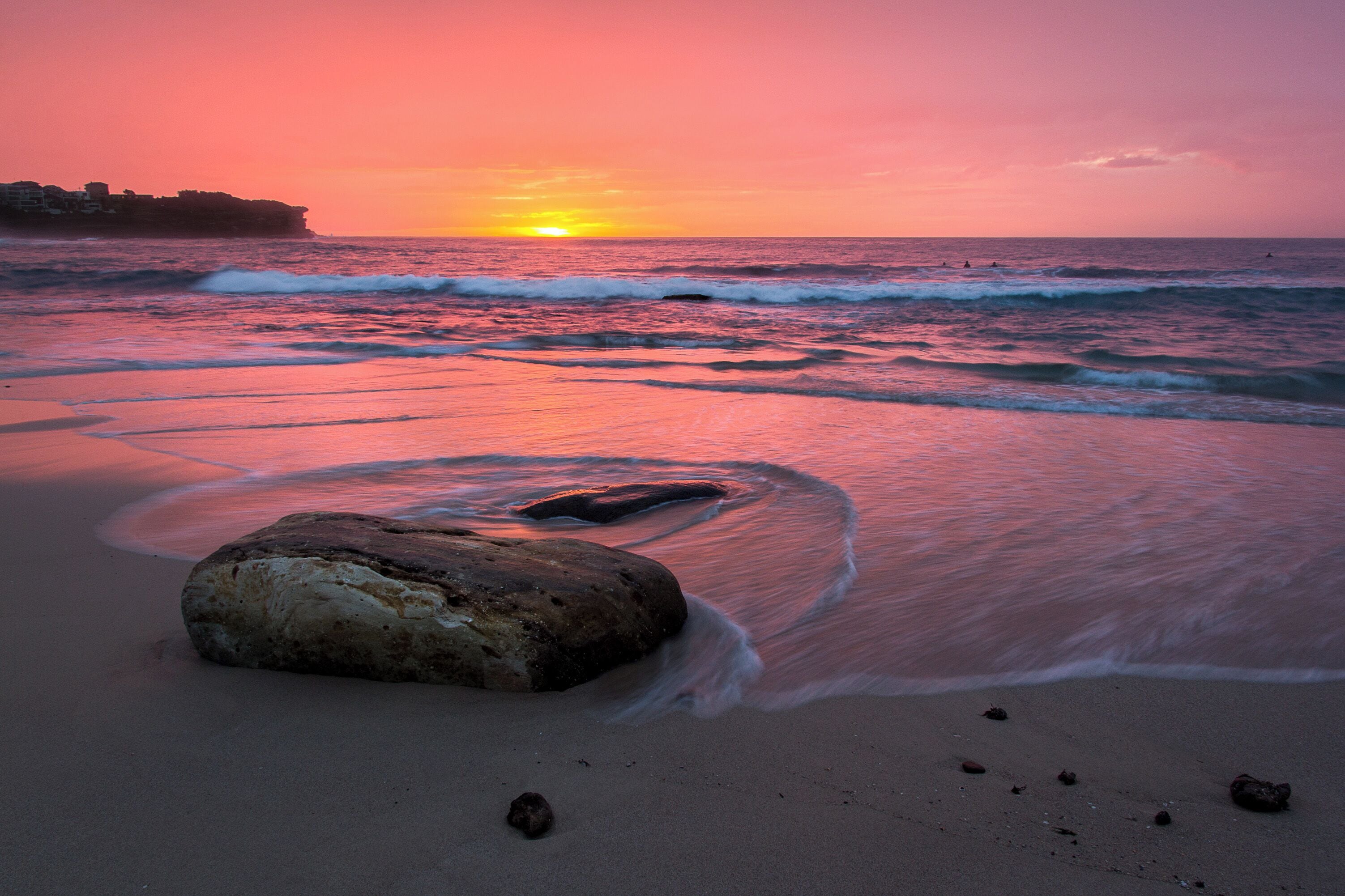 Bronte is popular with surfers as it gets larger waves than its neighbours. A couple can be seen in the water during this sunrise shot.