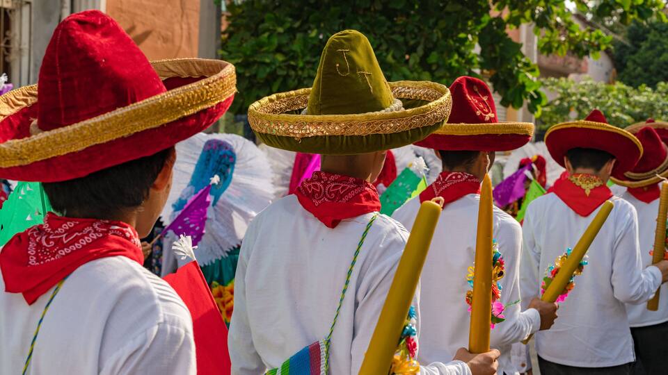 People wearing traditional hats and holding colorful staffs.