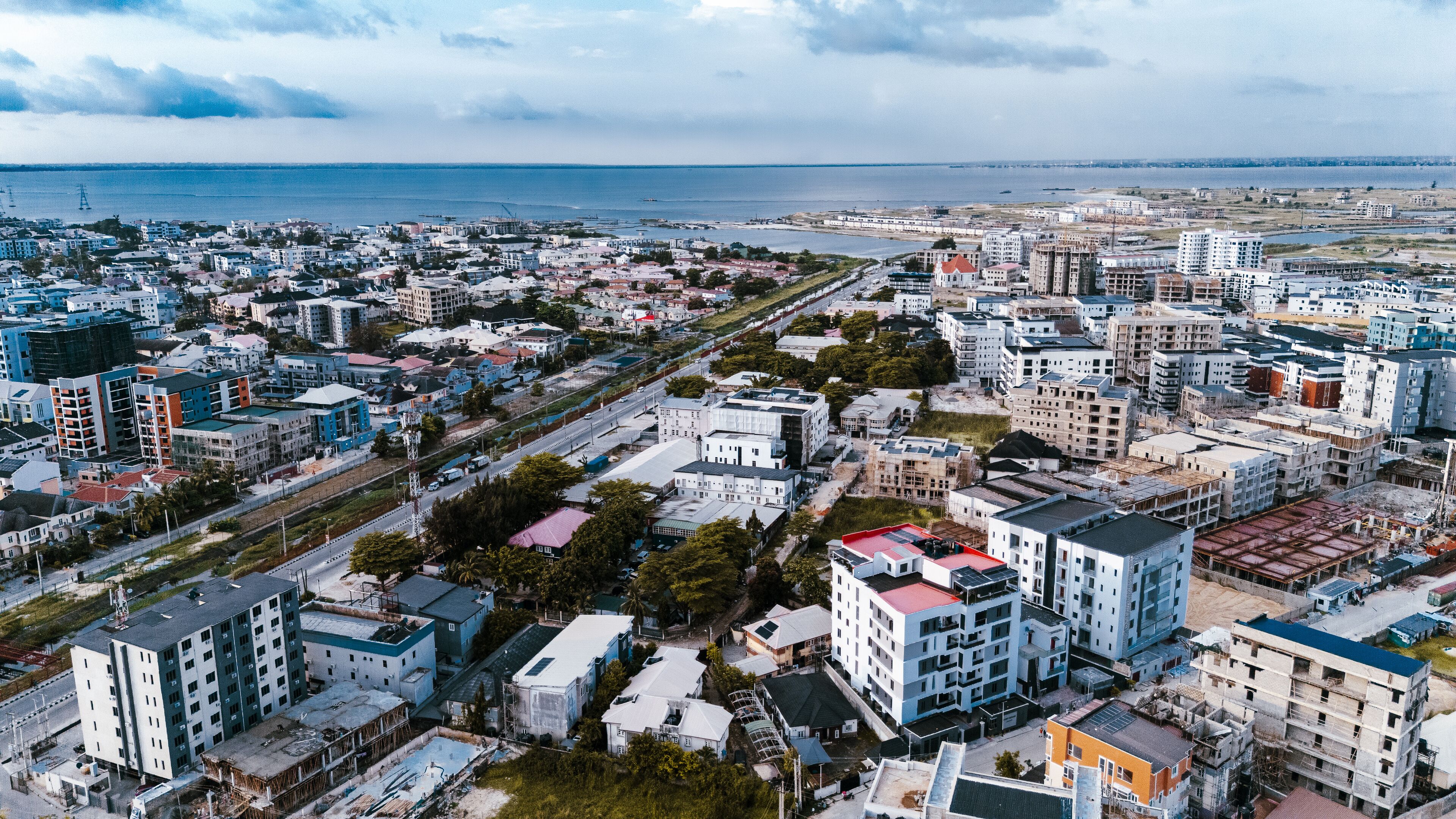 Aerial view of urban sprawl meets the ocean's edge, a tapestry of buildings contrasting with the blue horizon, Lekki, Lagos, Nigeria.