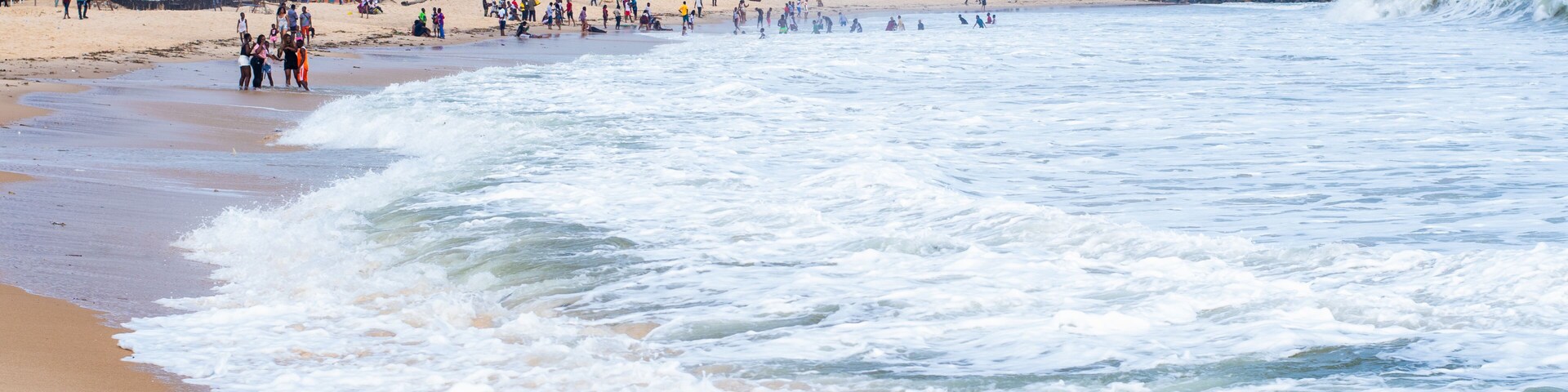 Una playa con olas, palmeras y edificios.