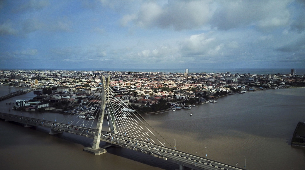 A cable-stayed bridge spanning a river, with a densely populated cityscape in the background.
