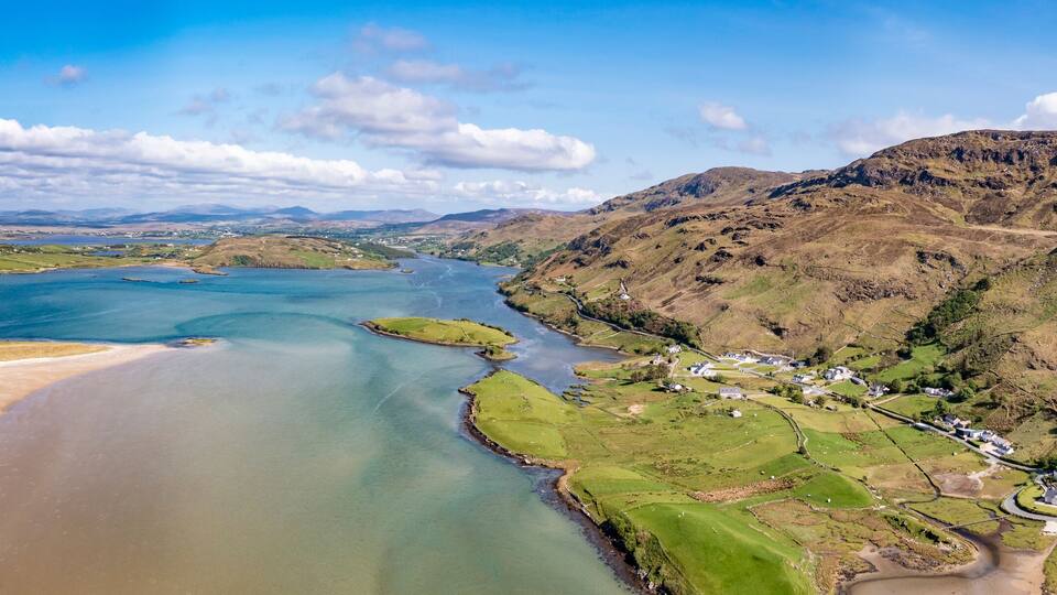 A river winding through a hilly landscape with green fields and scattered houses.