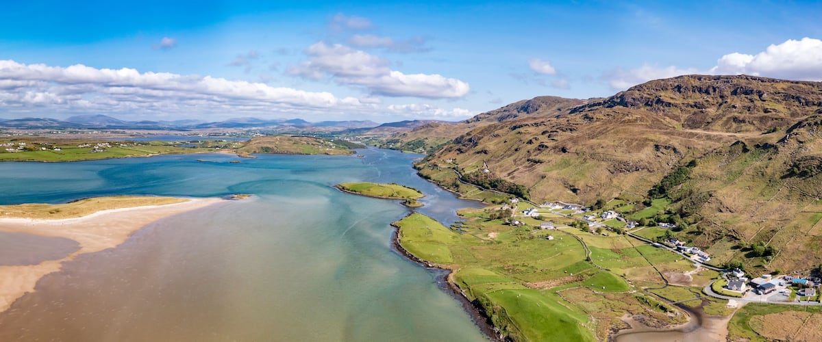 A river winding through a hilly landscape with green fields and scattered houses.