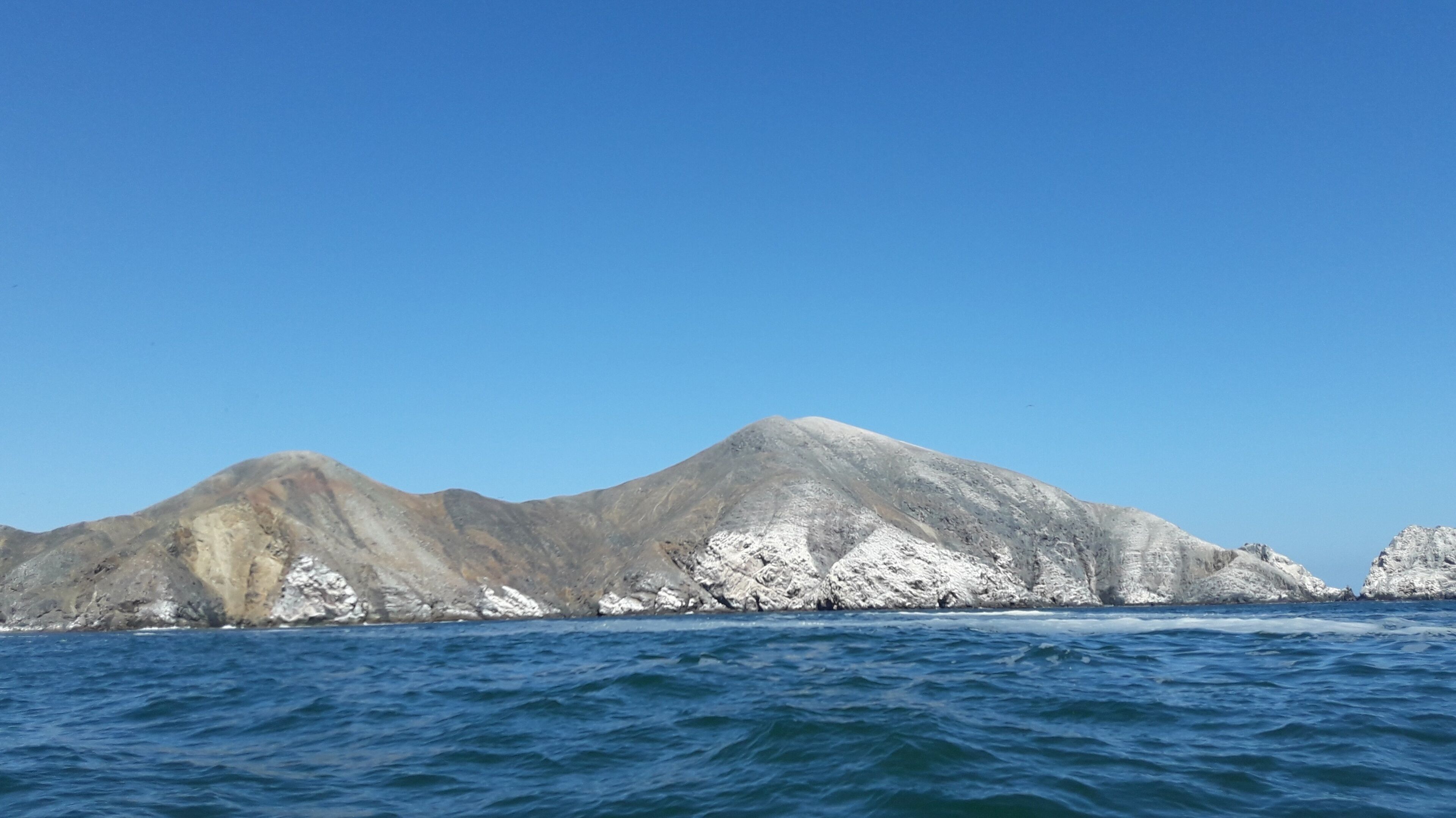 A mountain range with snow-capped peaks and a clear blue sky.