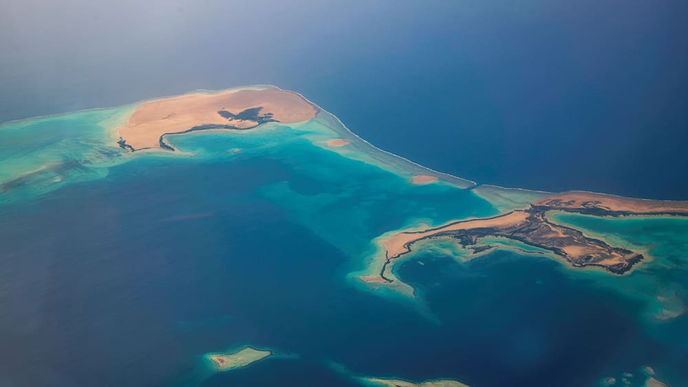 Vue aérienne d’une région côtière avec des eaux bleues et limpides, des plages de sable et plusieurs petites îles.