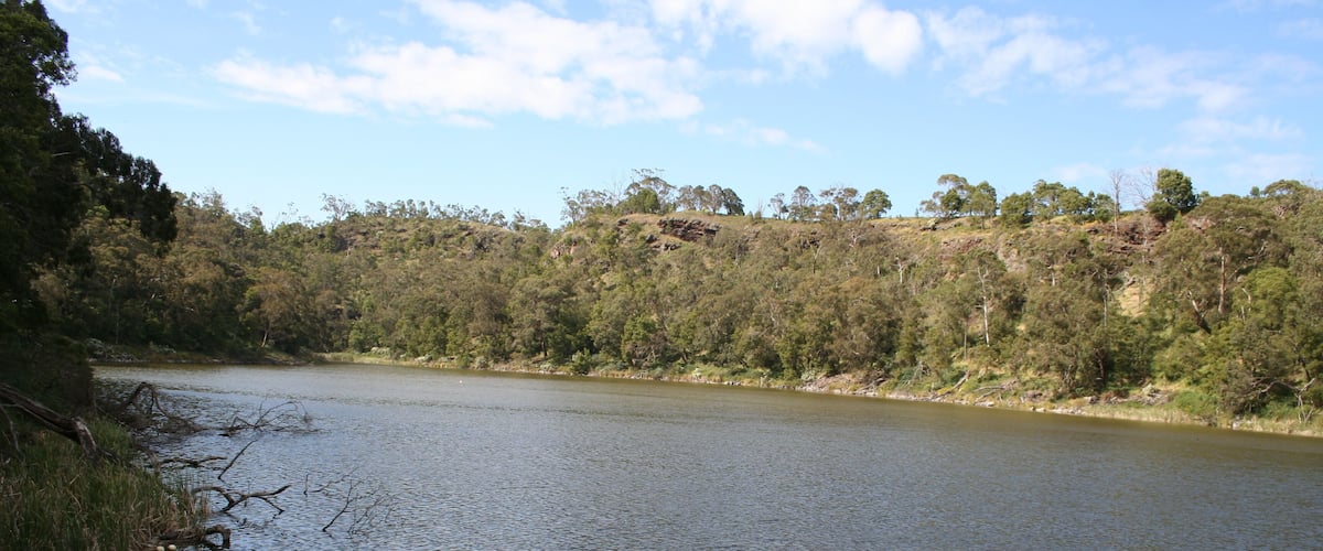 A calm lake surrounded by dense forest and hills.