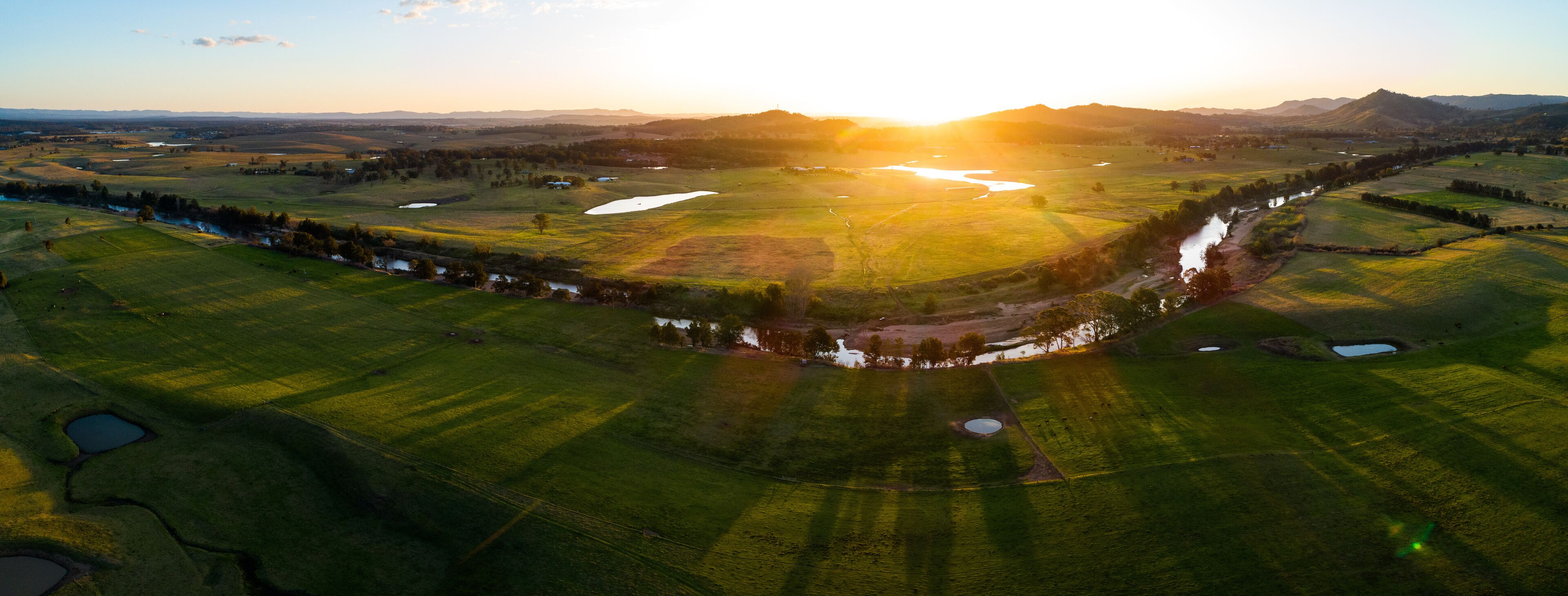 Panoramic view over Hunter River in green farmland at sunset 