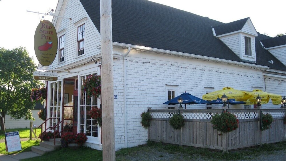 A white building with a sign reading "Red Shoe Pub." There are outdoor umbrellas and flower baskets.