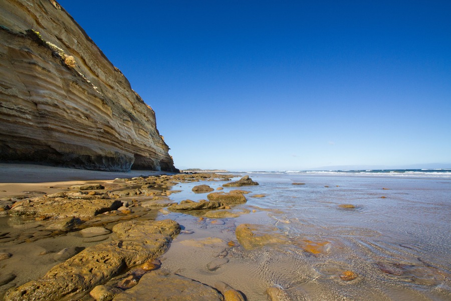 A rocky beach with cliffs and calm water.