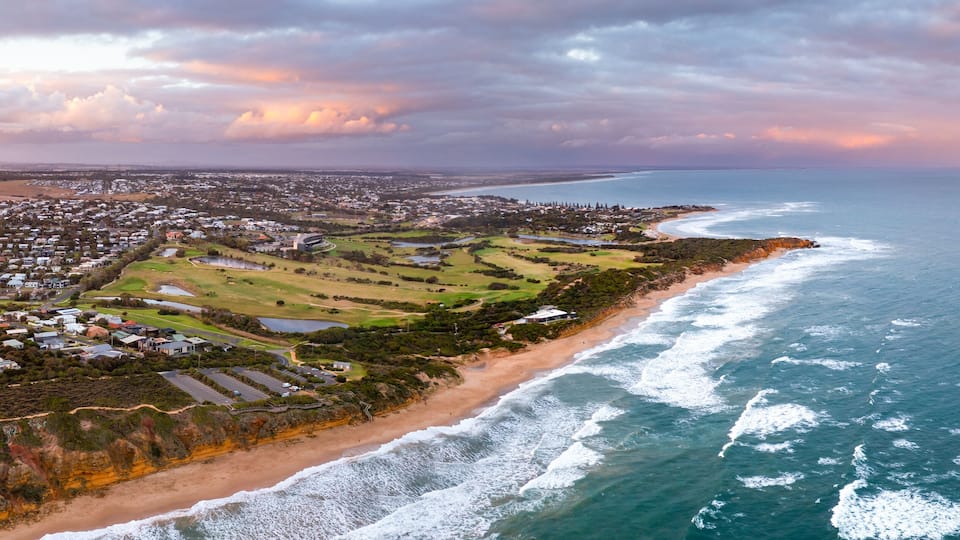 An aerial view of a coastal town with a beach, golf course, and residential area.