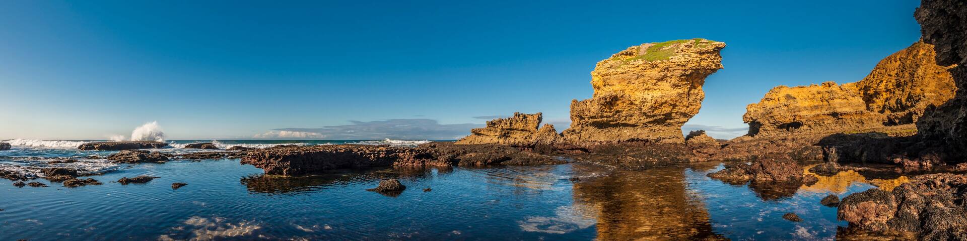 A coastal landscape with rocky formations and calm waters reflecting the sky.