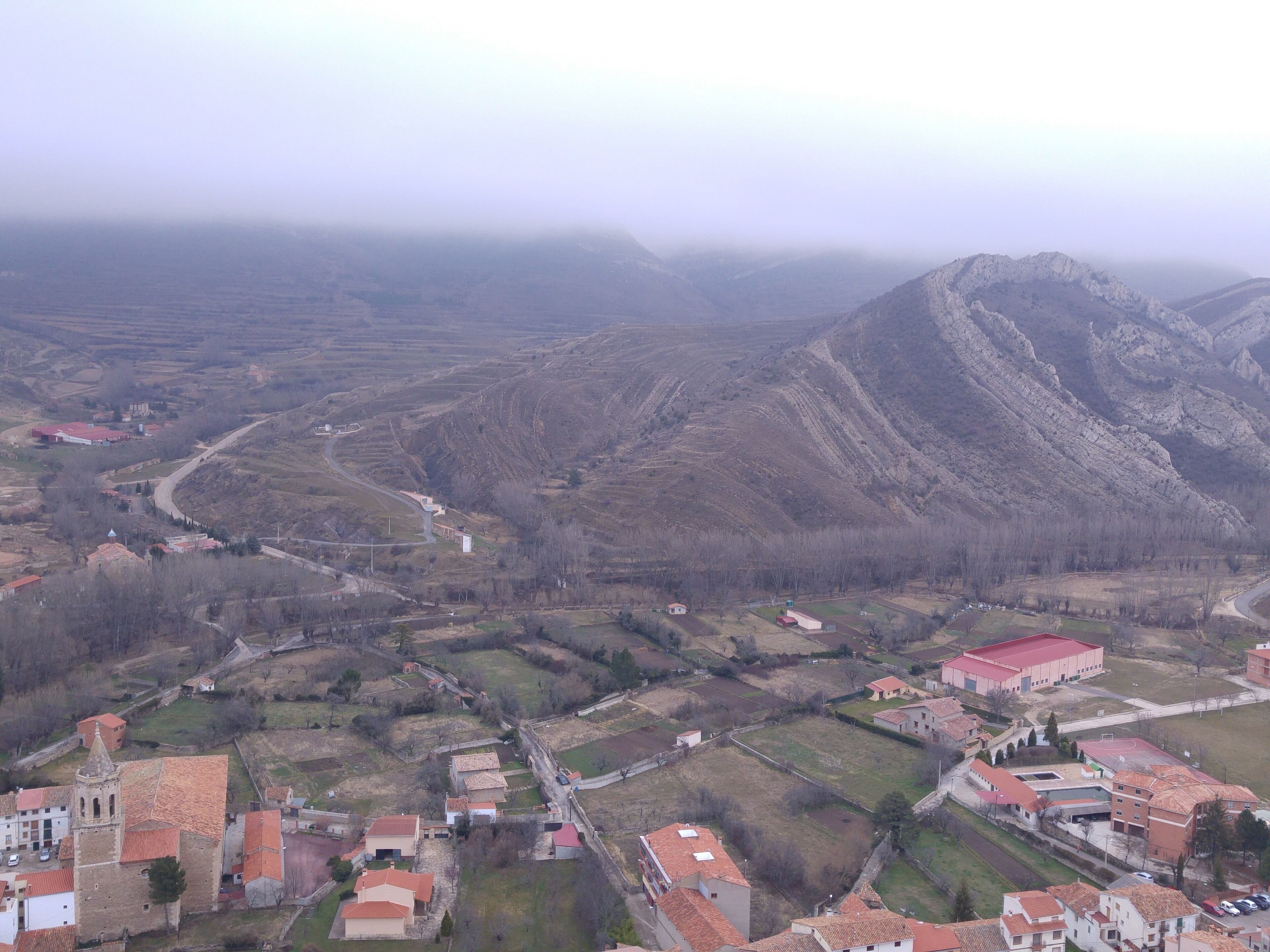 A mountainous landscape with a village featuring red-roofed buildings and a church.
