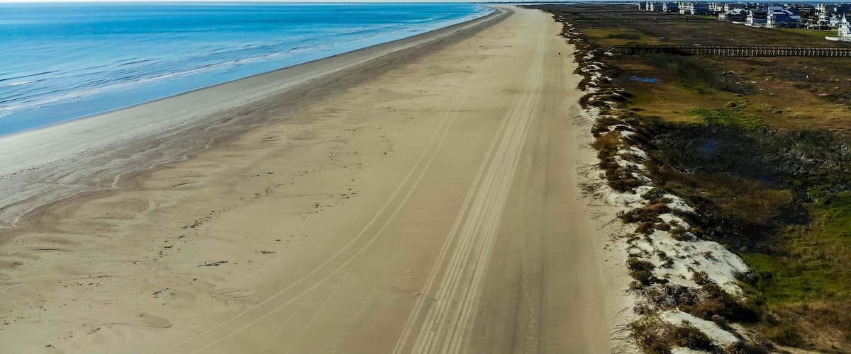 A long sandy beach with a clear blue sky and ocean.