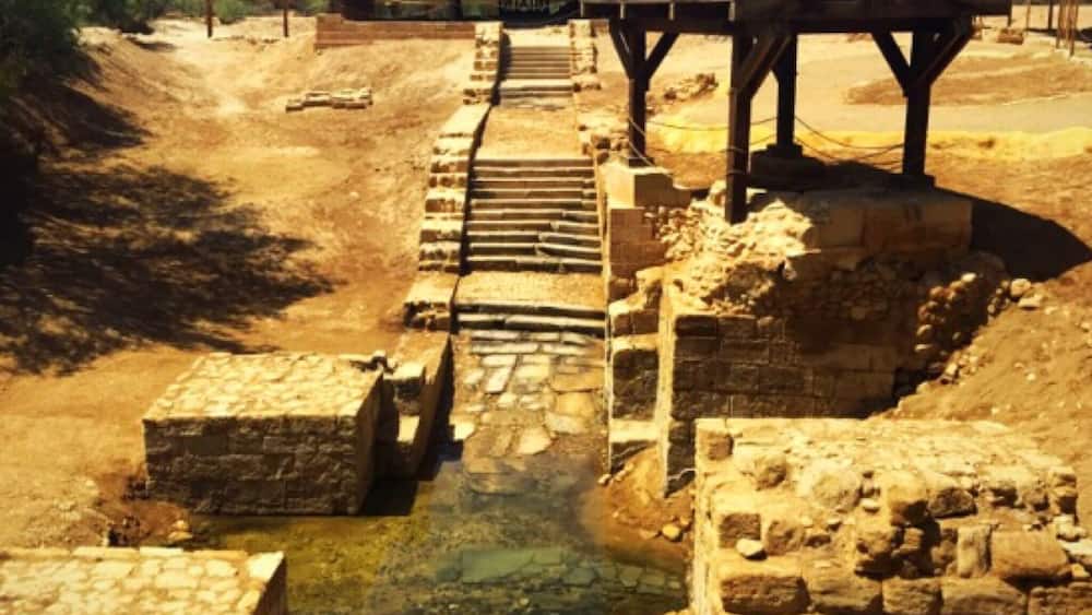 Une ancienne construction en pierre dotée d’un canal d’eau et de passerelles en bois.