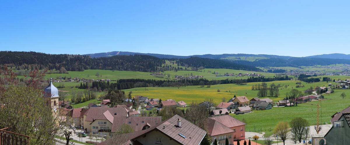 A village with houses, a church, and rolling hills in the background.