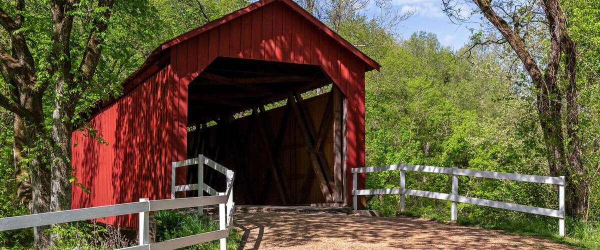A red covered bridge in a forest.