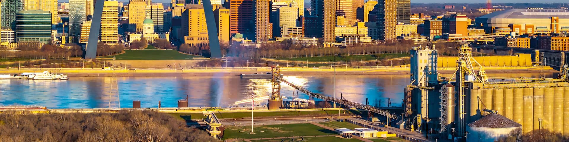 A city skyline with a prominent arch bridge, a river, and industrial buildings.