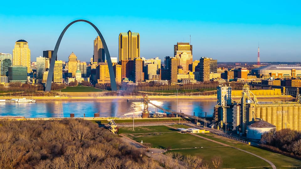 A city skyline with a prominent arch bridge, a river, and industrial buildings.