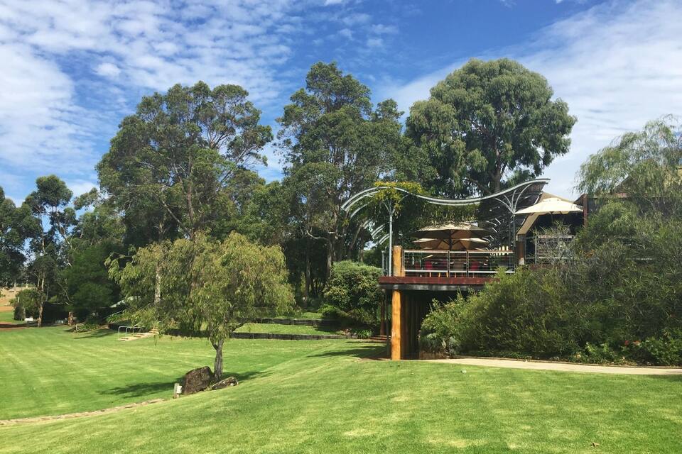 A well-maintained golf course with a pavilion, lush trees, and a clear blue sky.