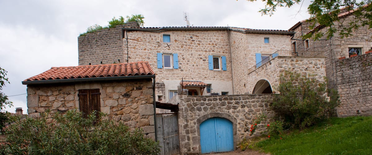 A stone building with a blue door and a red-tiled roof.