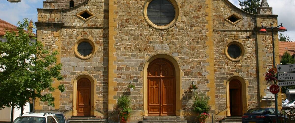 A historic church with a tall steeple, large arched doors, and a clock.