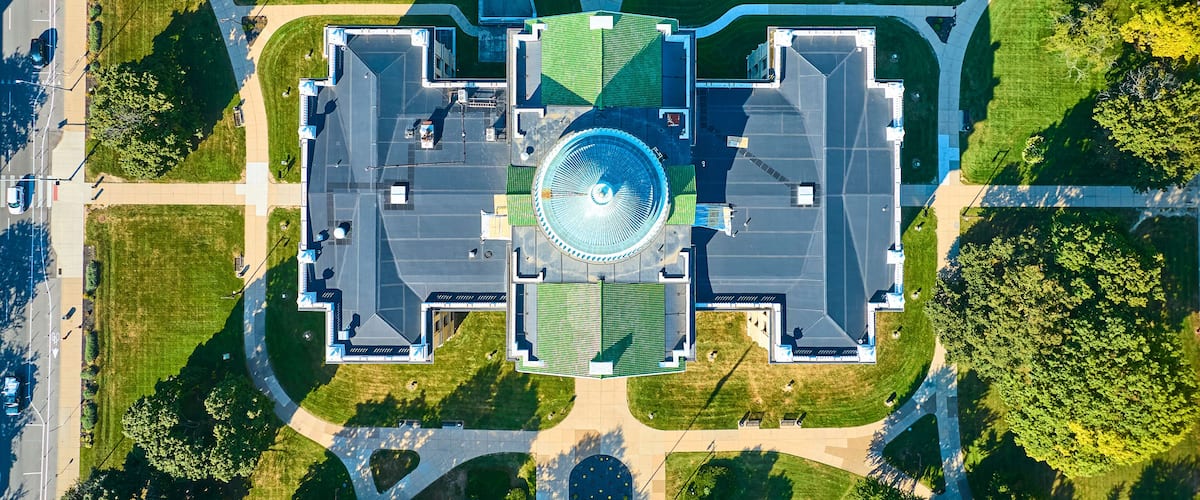 An aerial view of a circular plaza with a central fountain, surrounded by green lawns and pathways.