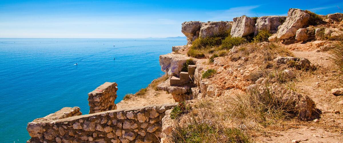 A coastal cliff with a stone staircase leading down to the beach.