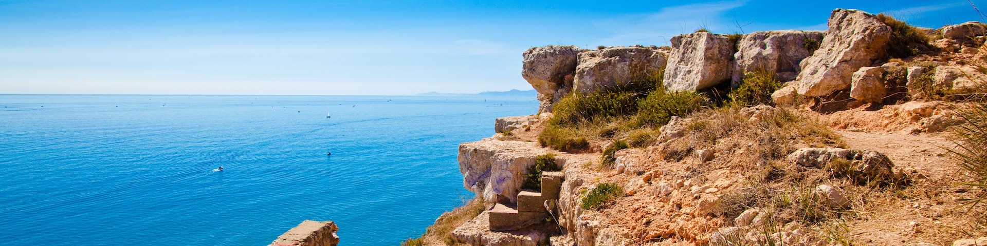 A coastal cliff with a stone staircase leading down to the beach.