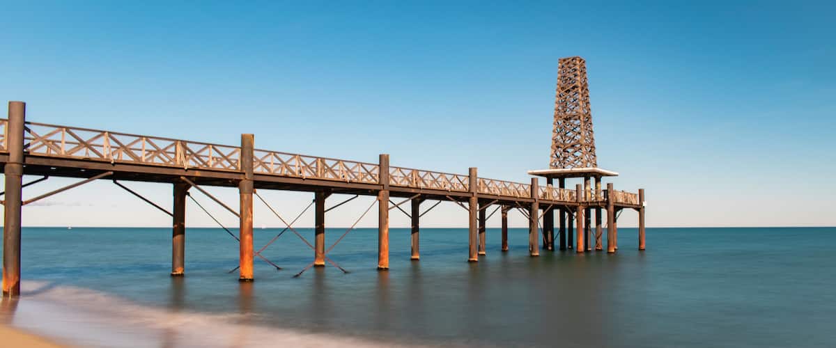 A long pier extending into calm waters with a clear sky above.